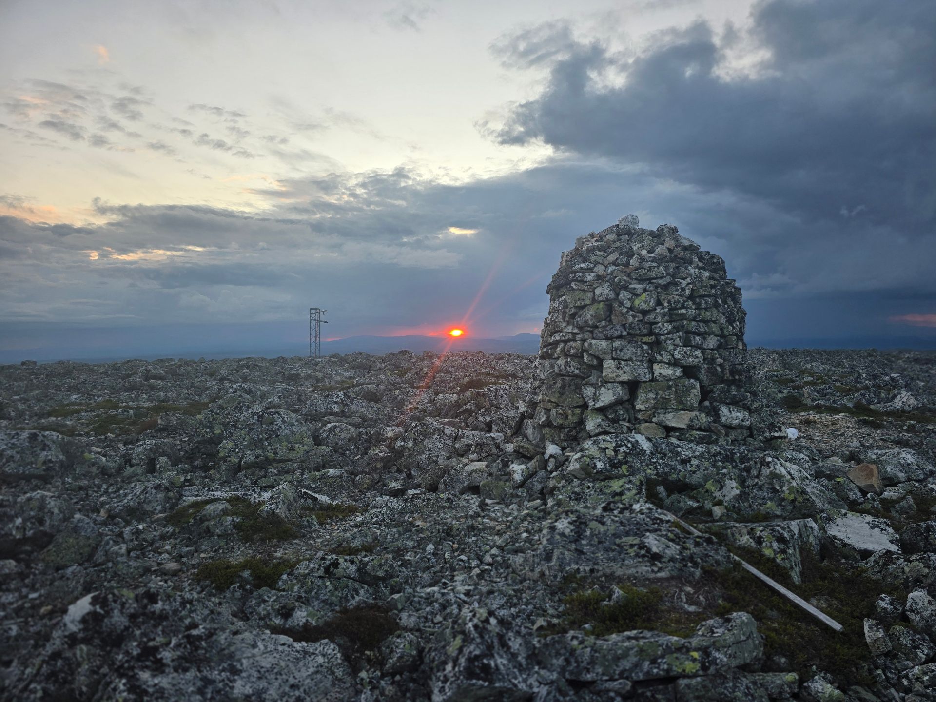 Röd solnedgång över fjällterräng med en stenröse i förgrunden i Vemdalen
